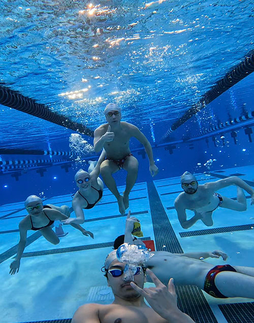 6 swimmers swimming at the camera underwater